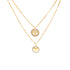 A pair of layered necklaces made from 14K gold-filled material is displayed against a white backdrop. The upper necklace showcases a delicate circle pendant with intricate patterns, while the lower piece highlights a larger circular pendant embellished with zirconia stones and featuring a central heart design, exuding elegance and charm. Named the "Heart and Tree of Life Zirconia Stones Pendant Necklace," these pieces are connected by a sophisticated box link chain.